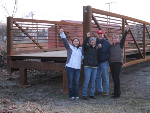 Ligonier Township Recreation Board members celebrate the arrival of the trail bridge to the Mill Creek location behind Weller Field. From left to right: Elizabeth McCall, President Sharon Detar, Larry Shew and Project Manager Rose Stepnick. (photo courtesy Rose Stepnick) 
